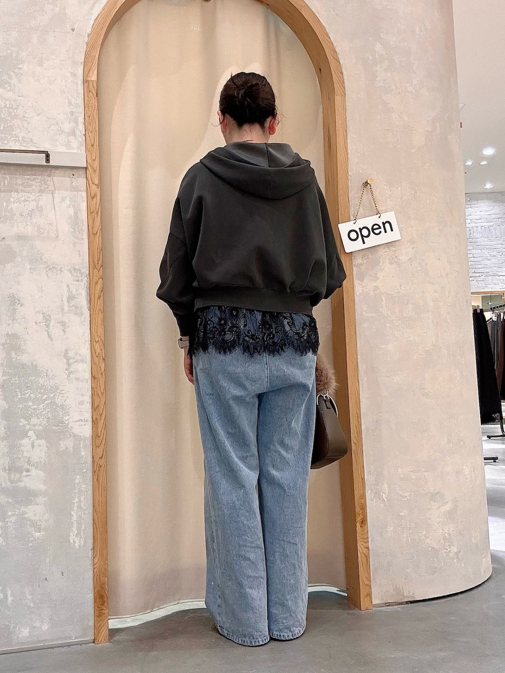 ブルー系のデニムパンツ、グリーン系のショルダーバッグ、ブラック系のTシャツ/カットソーを着用したレディースの秋コーディネートの3枚目の写真