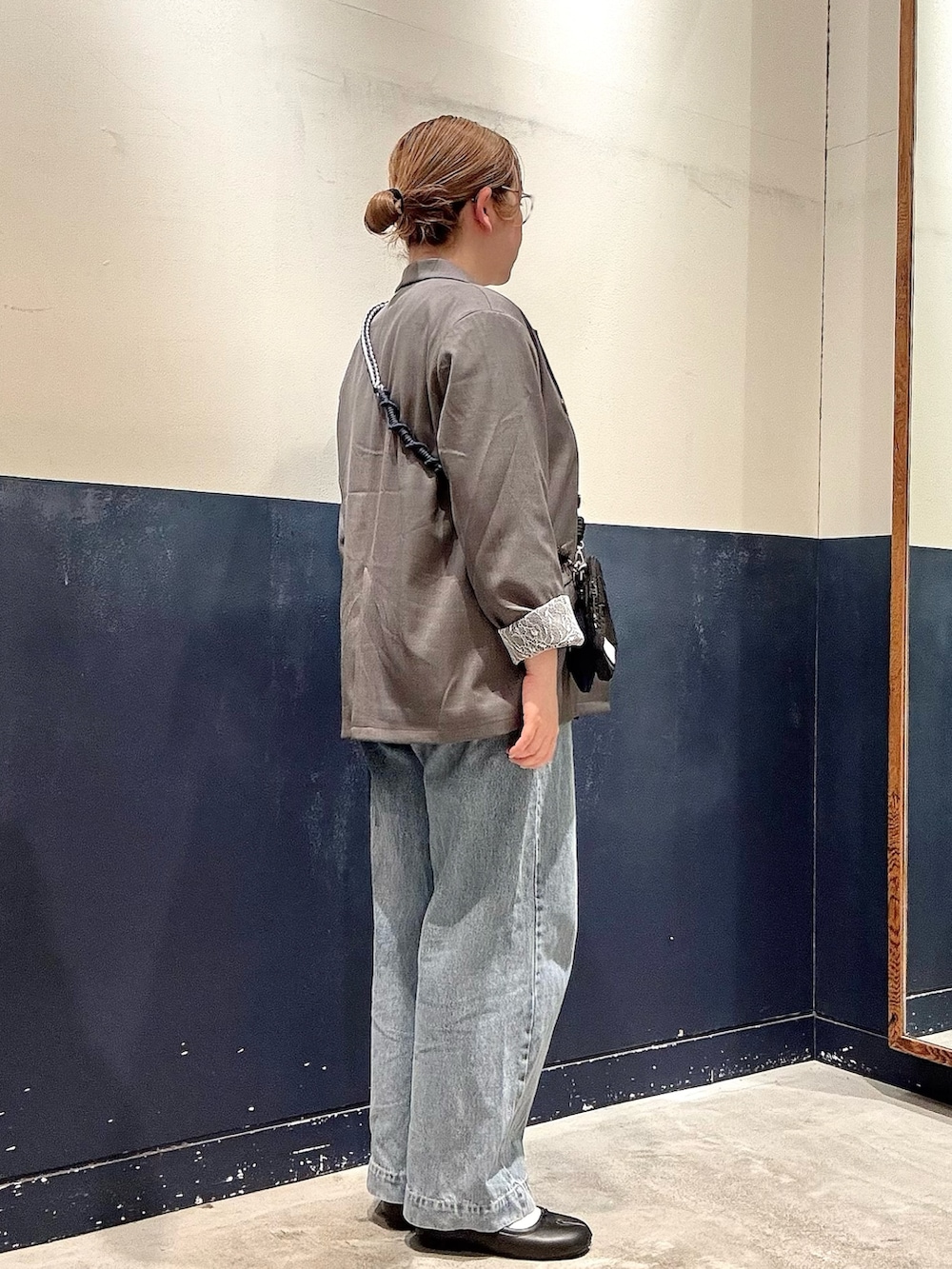 ブルー系のデニムパンツ、グレー系のテーラードジャケット、ブラック系のショルダーバッグを着用したレディースの春コーディネートの2枚目の写真