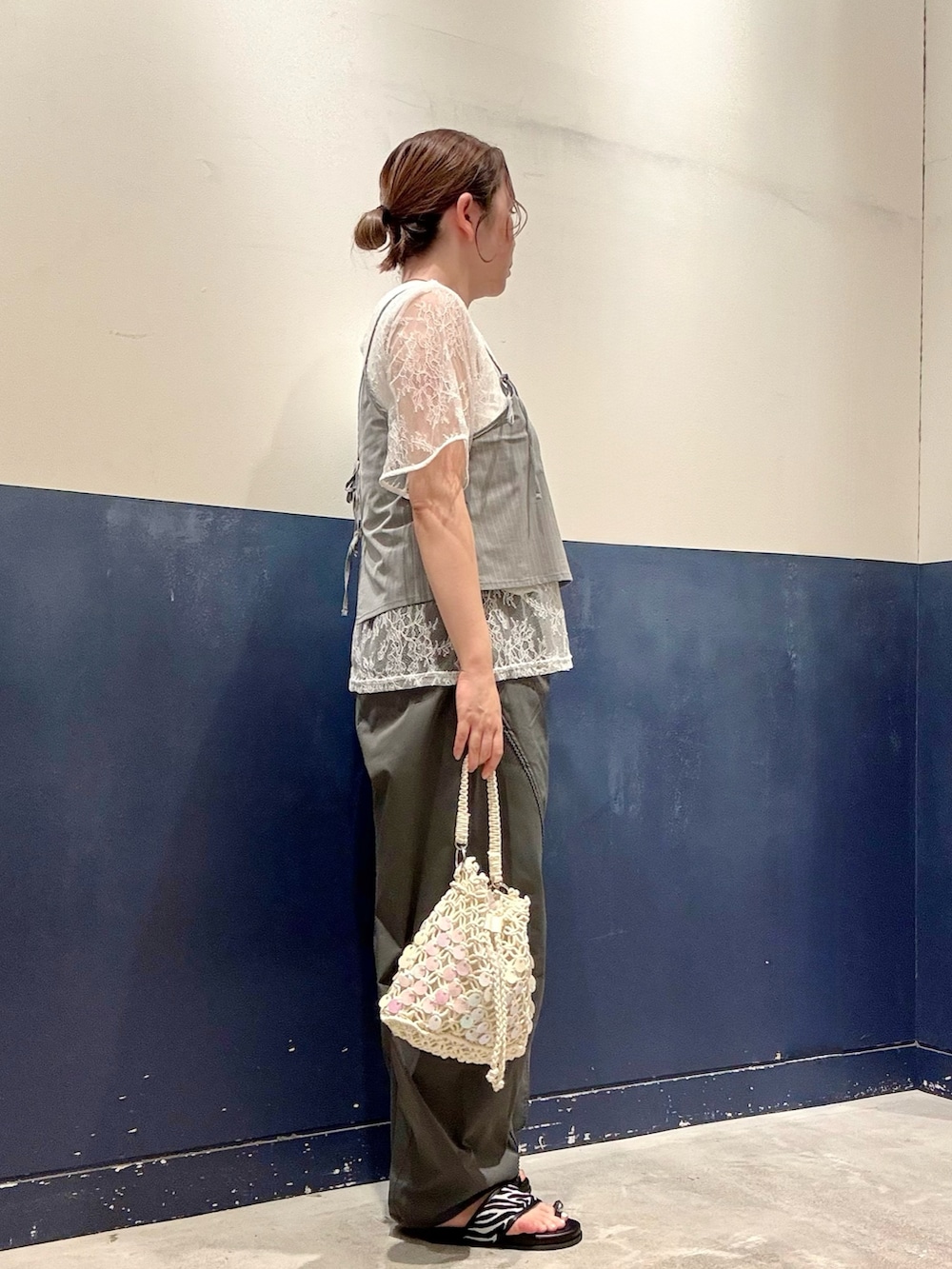 グレー系のその他パンツ、ブラック系のサンダル、ホワイト系のショルダーバッグを着用したレディースの夏コーディネートの2枚目の写真