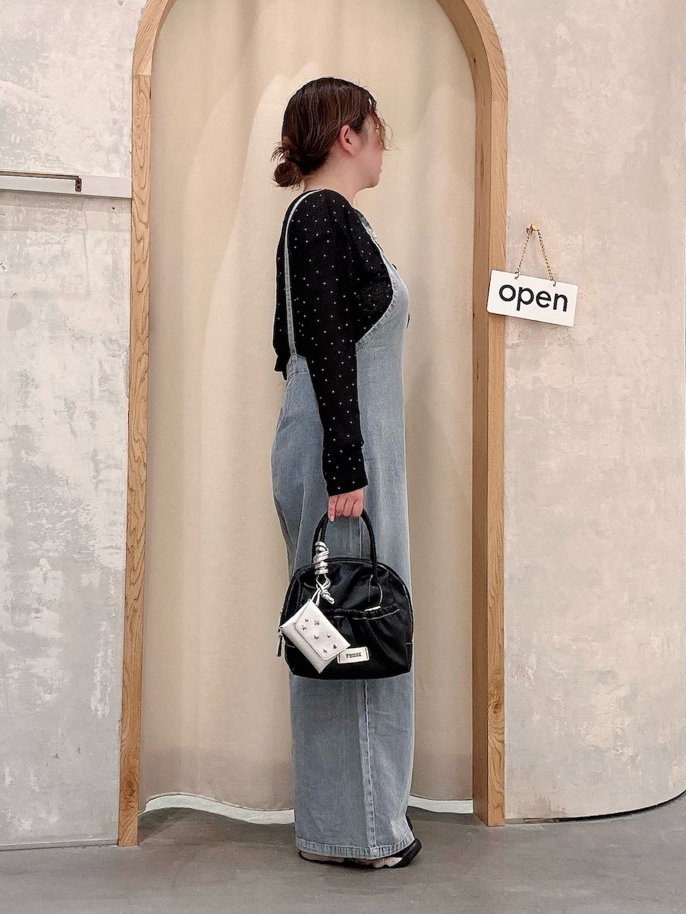 ブラック系のショルダーバッグ、ブルー系のサロペット/オーバーオール、ブラック系のTシャツ/カットソーを着用したレディースの夏コーディネートの2枚目の写真