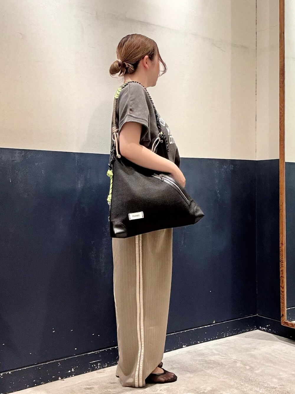 ブラック系のパンプス、ブラック系のショルダーバッグ、ベージュ系のスラックスを着用したレディースの春コーディネートの2枚目の写真