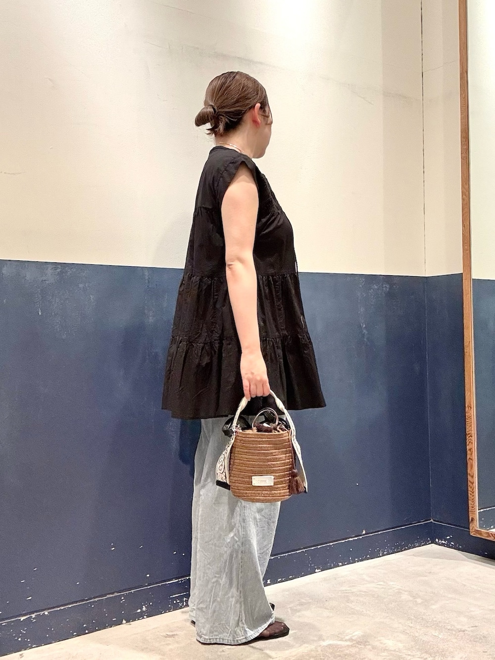 ブラック系のパンプス、ブルー系のデニムパンツ、ブラウン系のトートバッグを着用したレディースの夏コーディネートの2枚目の写真
