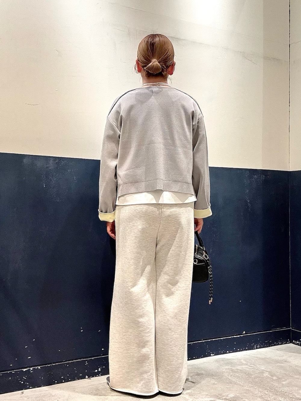 シルバー系のパンプス、ブラック系のショルダーバッグ、ホワイト系のスウェットパンツを着用したレディースの冬コーディネートの3枚目の写真