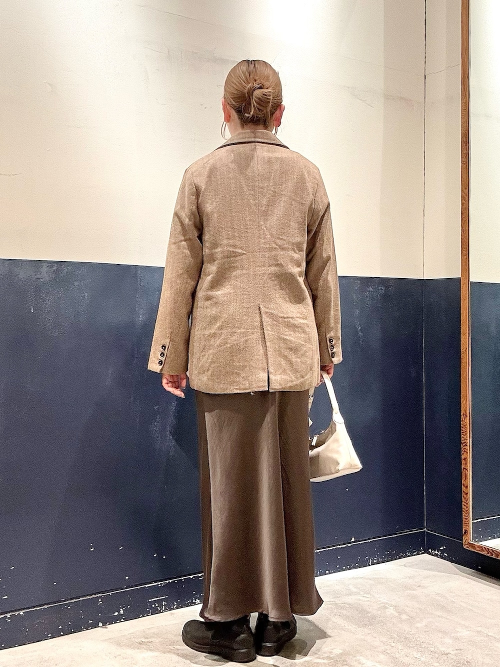 グレー系のショルダーバッグ、グレー系のスカート、ホワイト系のTシャツ/カットソーを着用したレディースの冬コーディネートの3枚目の写真