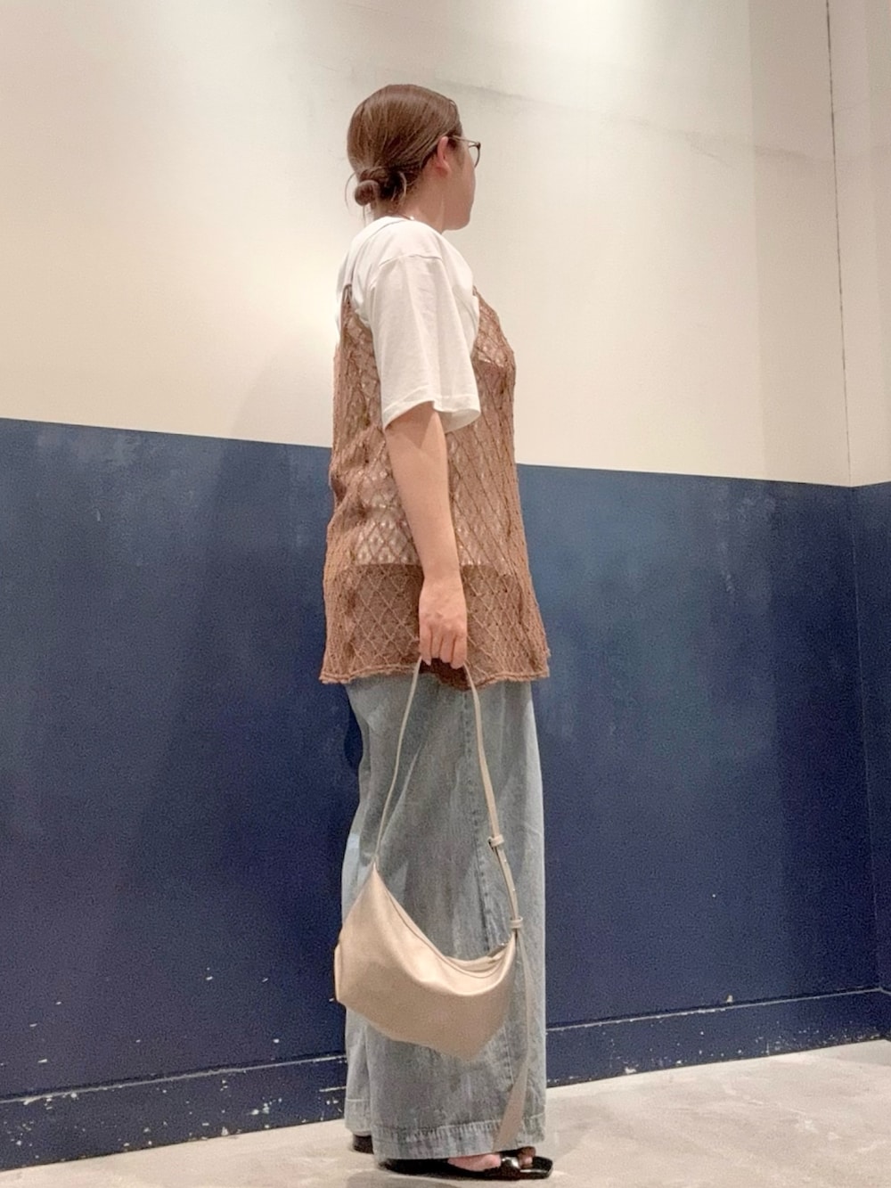 ブルー系のデニムパンツ、ブラック系のサンダル、ホワイト系のTシャツ/カットソーを着用したレディースの夏コーディネートの2枚目の写真