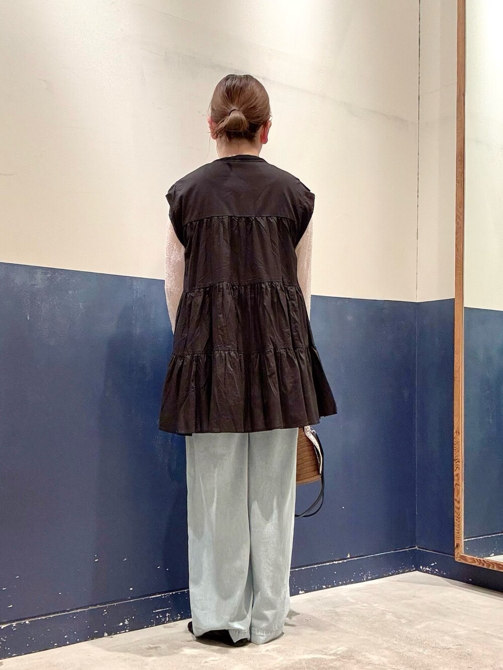 ブラック系のパンプス、ブラウン系のトートバッグ、ブルー系のデニムパンツを着用したレディースの夏コーディネートの3枚目の写真