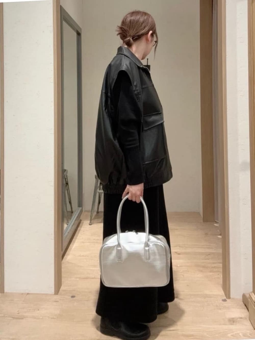 ブラック系のライダースジャケット、ブラック系のワンピース、シルバー系のボストンバッグを着用したレディースの秋コーディネートの2枚目の写真