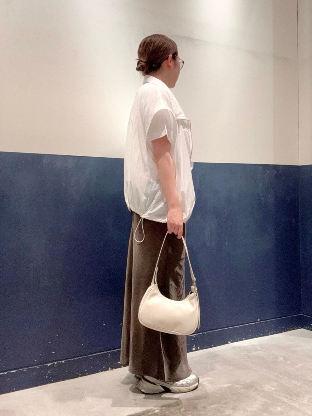 グレー系のスカート、ホワイト系のナイロンジャケット、グレー系のTシャツ/カットソーを着用したレディースの夏コーディネートの2枚目の写真