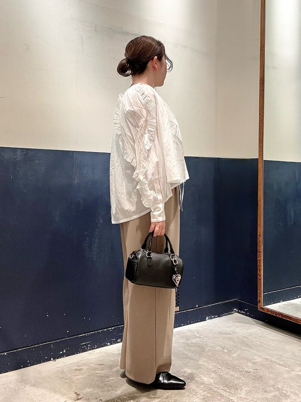 ブラック系のパンプス、ブラック系のショルダーバッグ、ホワイト系のタンクトップを着用したレディースの春コーディネートの2枚目の写真