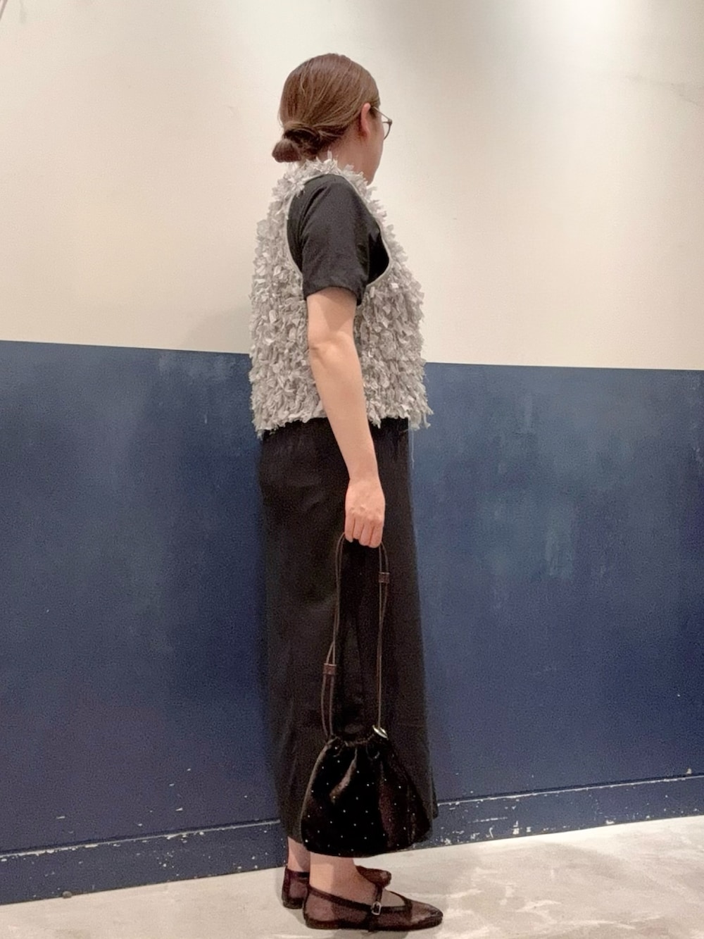 ブラック系のワンピース、ブラック系のパンプス、グレー系のベストを着用したレディースの夏コーディネートの2枚目の写真