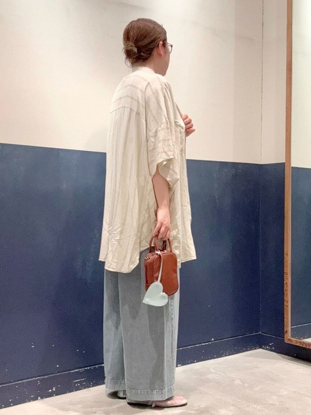 ベージュ系のシャツ/ブラウス、ブルー系のデニムパンツ、ブラウン系のトートバッグを着用したレディースの夏コーディネートの2枚目の写真