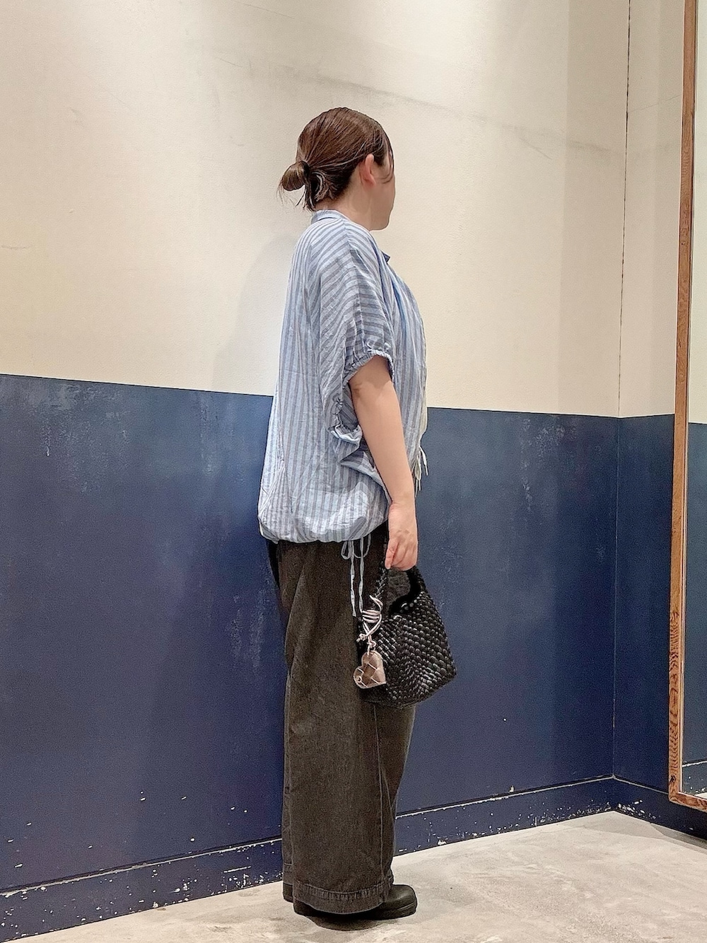 ブラック系のショルダーバッグ、ブラック系のデニムパンツ、ブルー系のシャツ/ブラウスを着用したレディースの夏コーディネートの2枚目の写真