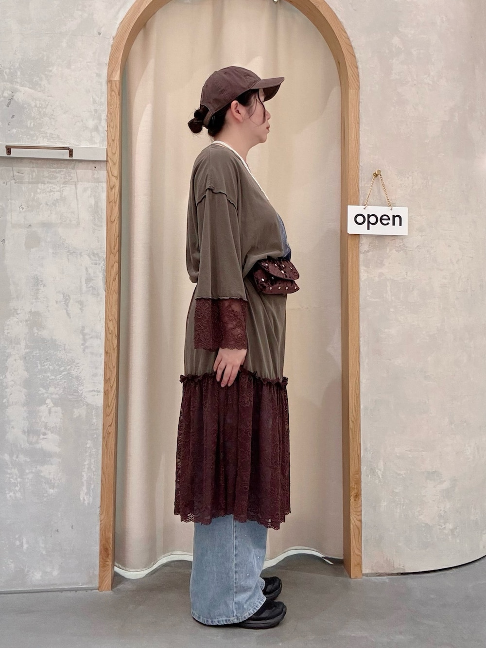 ブルー系のデニムパンツ、ブラウン系のボディバッグ/ウエストポーチ、ブラウン系のワンピースを着用したレディースの秋コーディネートの2枚目の写真