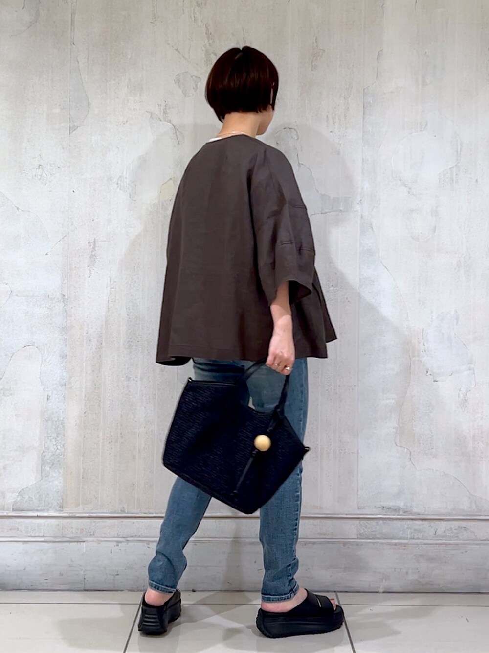 グレー系のブルゾン、ホワイト系のTシャツ/カットソー、ブルー系のデニムパンツを着用したレディースの夏コーディネートの2枚目の写真