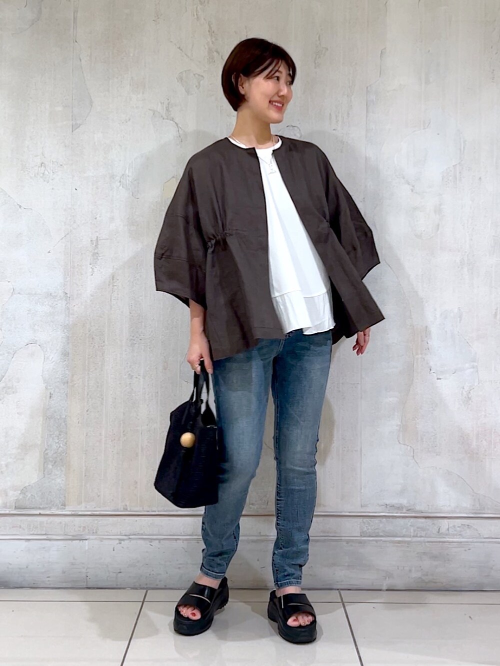 グレー系のブルゾン、ホワイト系のTシャツ/カットソー、ブルー系のデニムパンツを着用したレディースの夏コーディネートの5枚目の写真