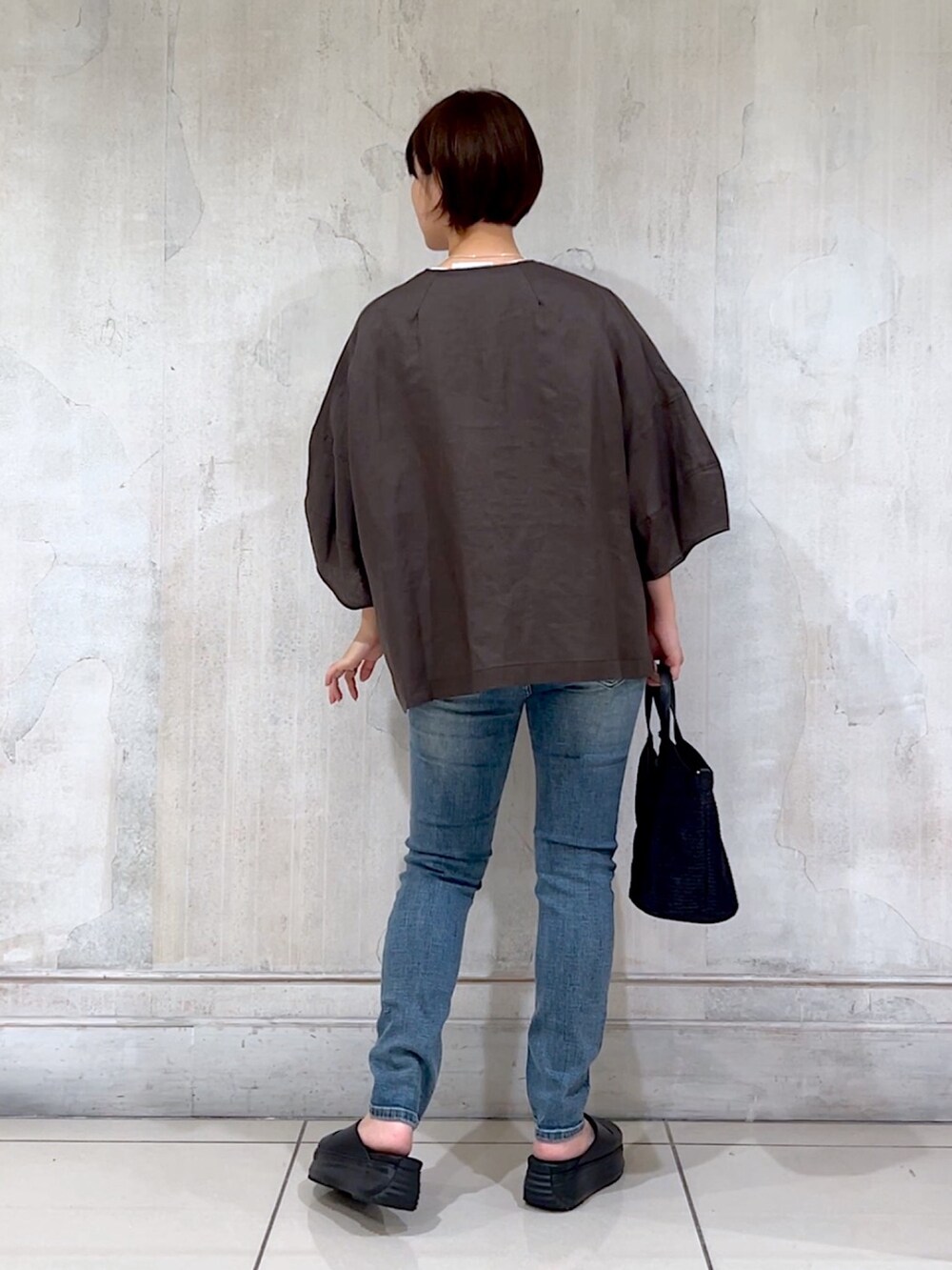 グレー系のブルゾン、ホワイト系のTシャツ/カットソー、ブルー系のデニムパンツを着用したレディースの夏コーディネートの3枚目の写真