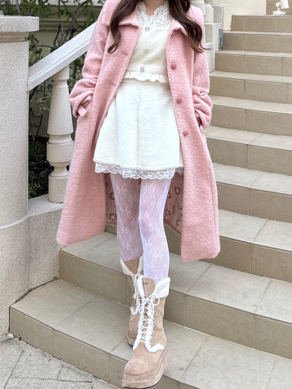 ピンク系のジャケット/アウター、ベージュ系のブーツ、ホワイト系のタイツ/ストッキングを着用したレディースの冬コーディネートの2枚目の写真