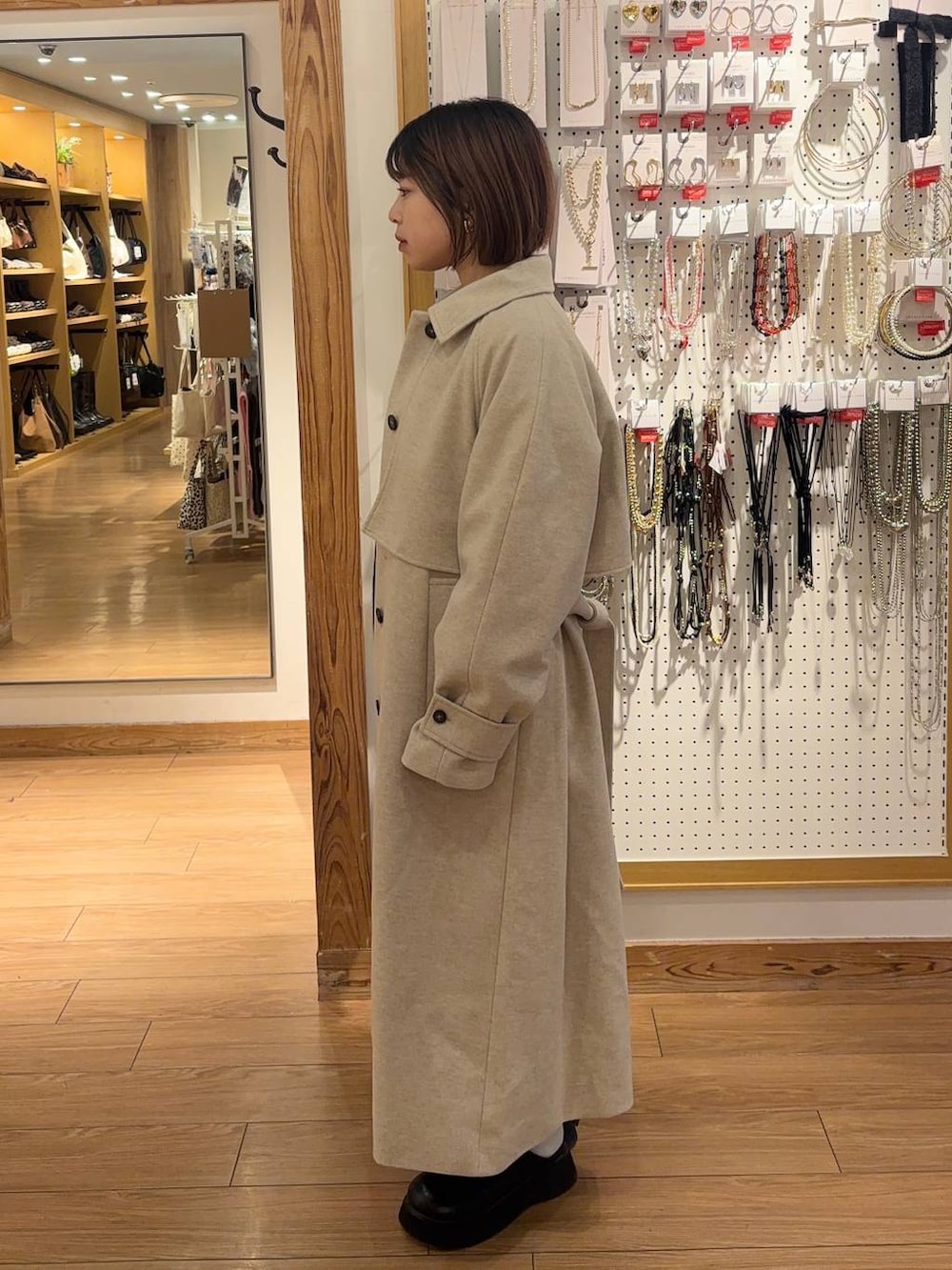 ホワイト系のステンカラーコート、ブラック系のサンダル、グレー系のスカートを着用したレディースの冬コーディネートの2枚目の写真