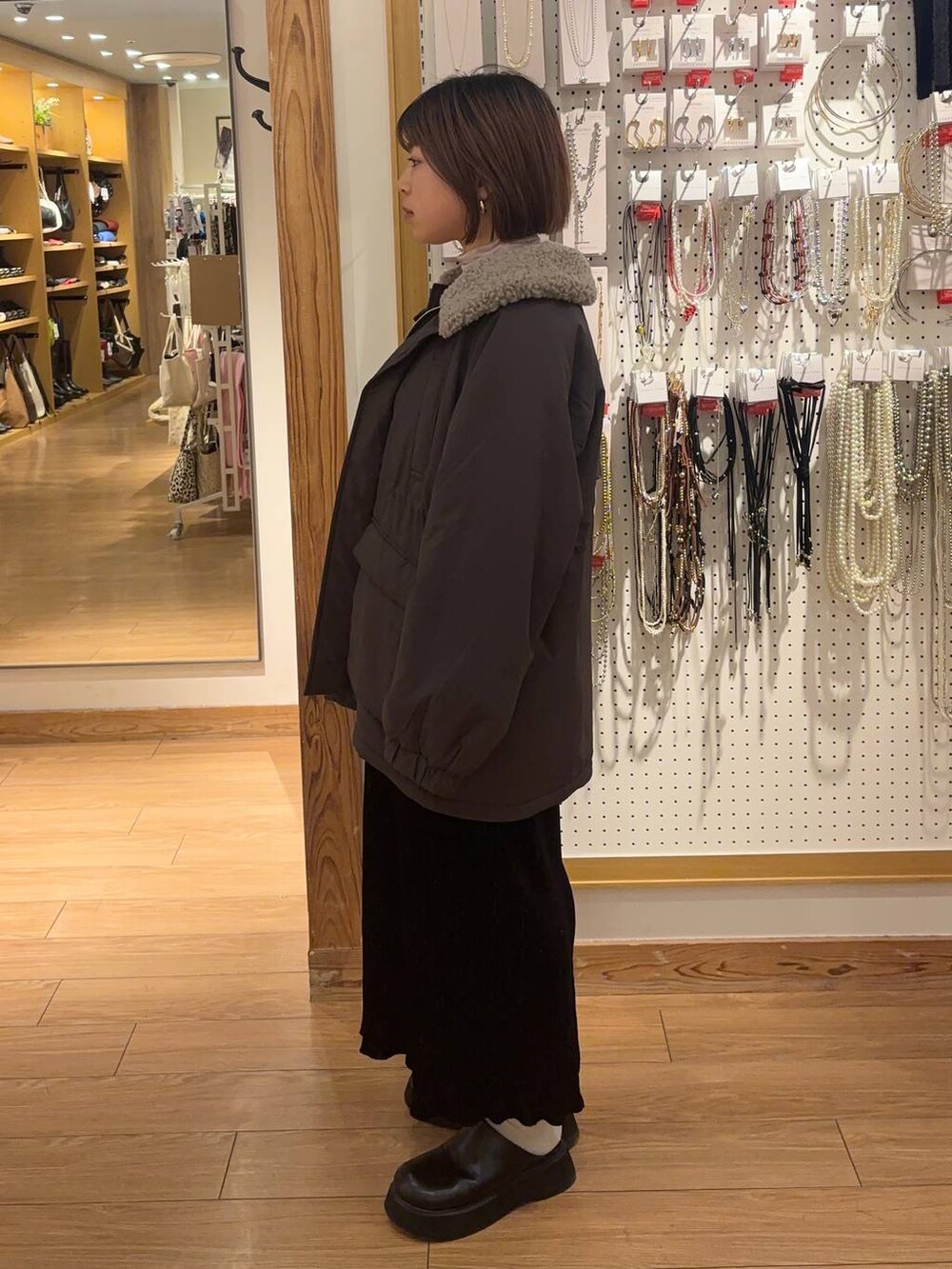 グレー系のその他アウター、ブラック系のサンダル、ブラック系のスカートを着用したレディースの冬コーディネートの2枚目の写真