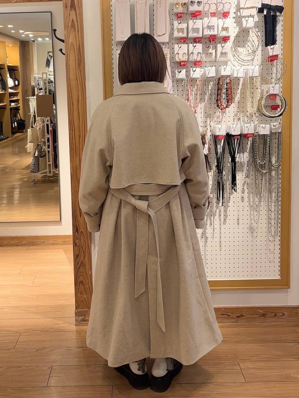 ホワイト系のステンカラーコート、ブラック系のサンダル、グレー系のスカートを着用したレディースの冬コーディネートの3枚目の写真