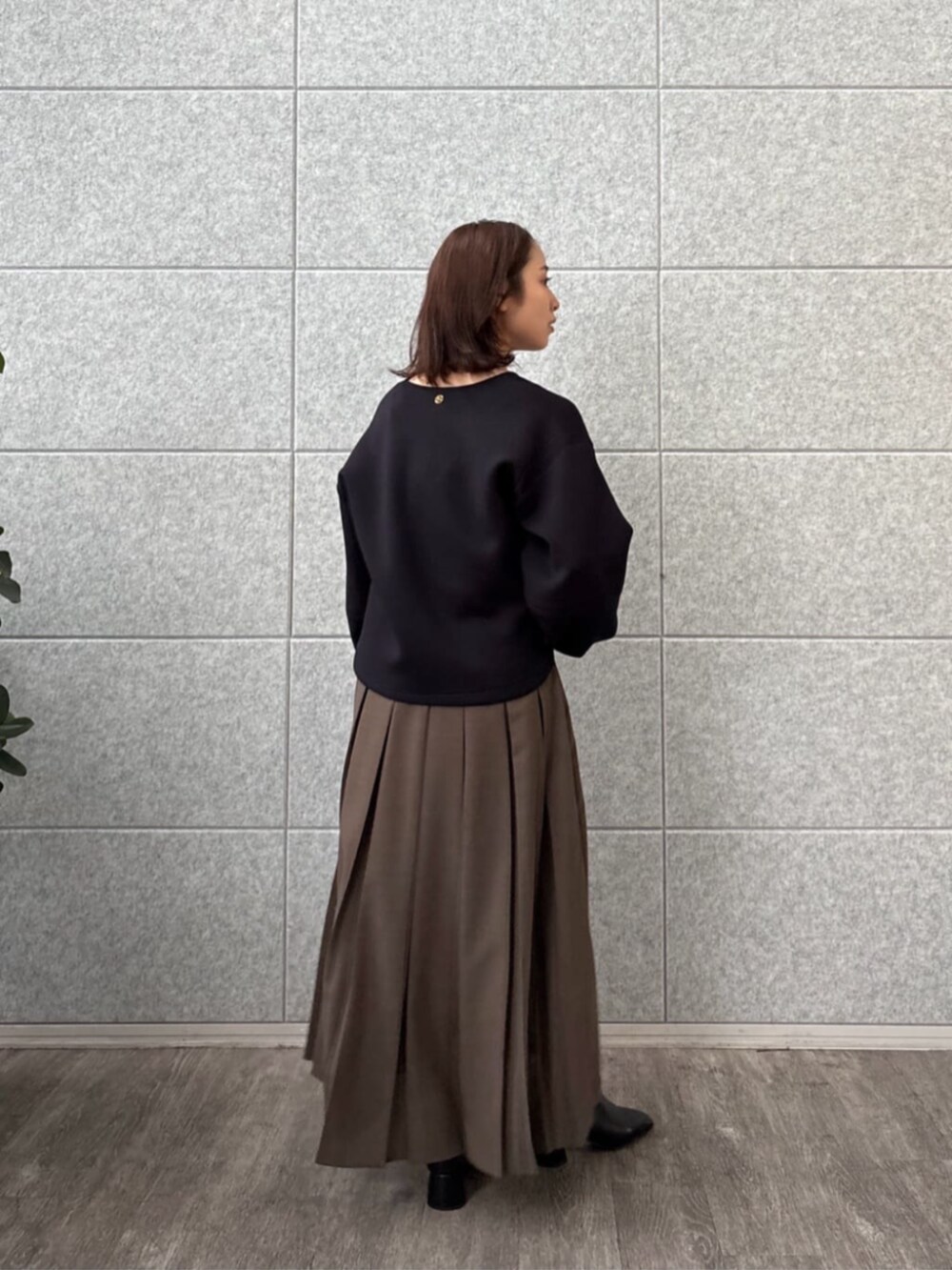 ブラウン系のスカート、ブラック系のTシャツ/カットソーを着用したレディースの秋コーディネートの2枚目の写真