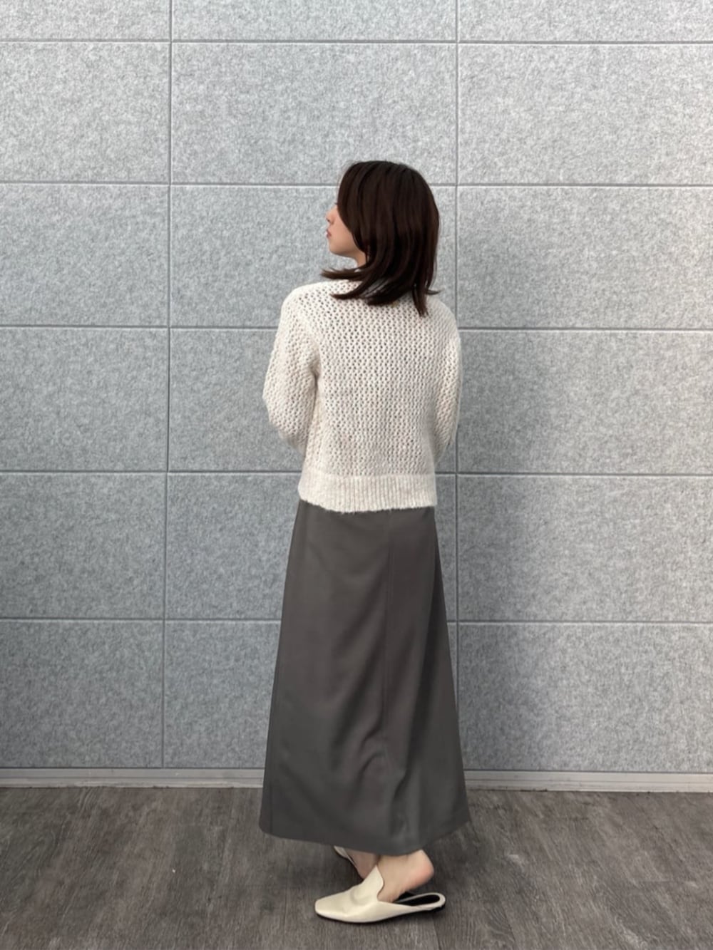 グレー系のスカート、ホワイト系のニット/セーターを着用したレディースの秋コーディネートの3枚目の写真