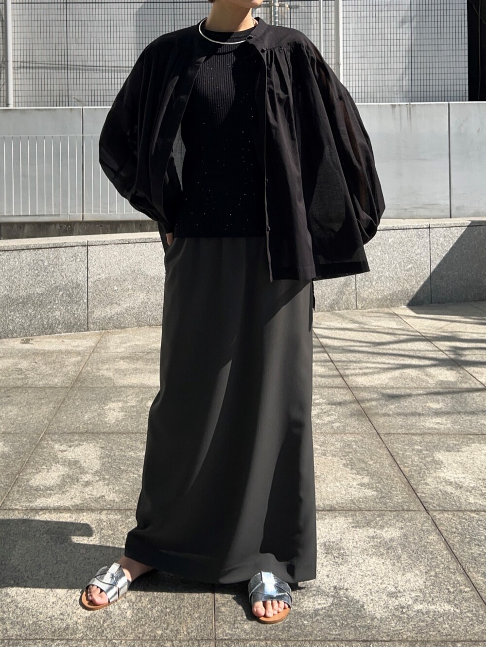 ブラック系のニット/セーター、グレー系のスカート、ブラック系のシャツ/ブラウスを着用したレディースの春コーディネートの8枚目の写真