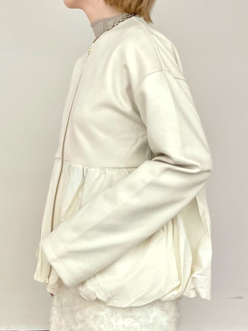 ホワイト系のスカート、ゴールド系のニット/セーター、ホワイト系のブルゾンを着用したレディースの冬コーディネートの5枚目の写真