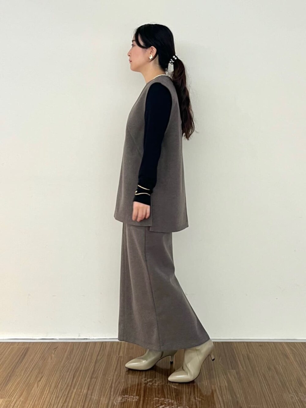 ブラウン系のベスト、ブラウン系のスカート、ブラック系のTシャツ/カットソーを着用したレディースの秋コーディネートの3枚目の写真