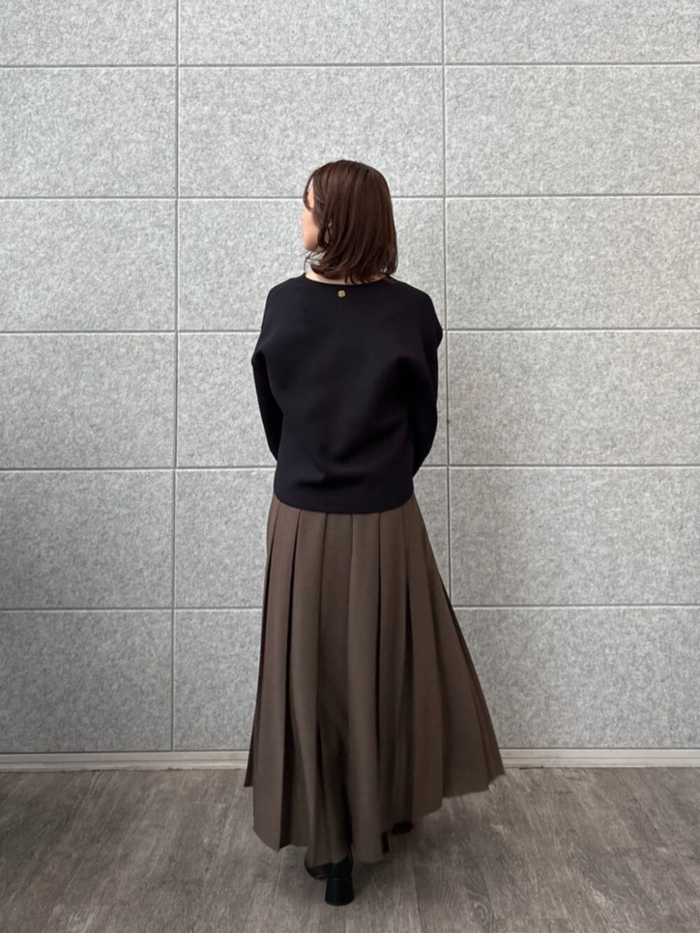 ブラウン系のスカート、ブラック系のTシャツ/カットソーを着用したレディースの秋コーディネートの4枚目の写真