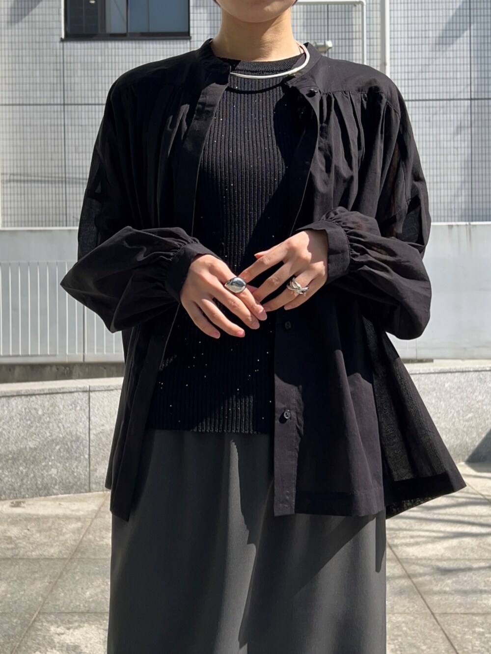 ブラック系のニット/セーター、グレー系のスカート、ブラック系のシャツ/ブラウスを着用したレディースの春コーディネートの7枚目の写真