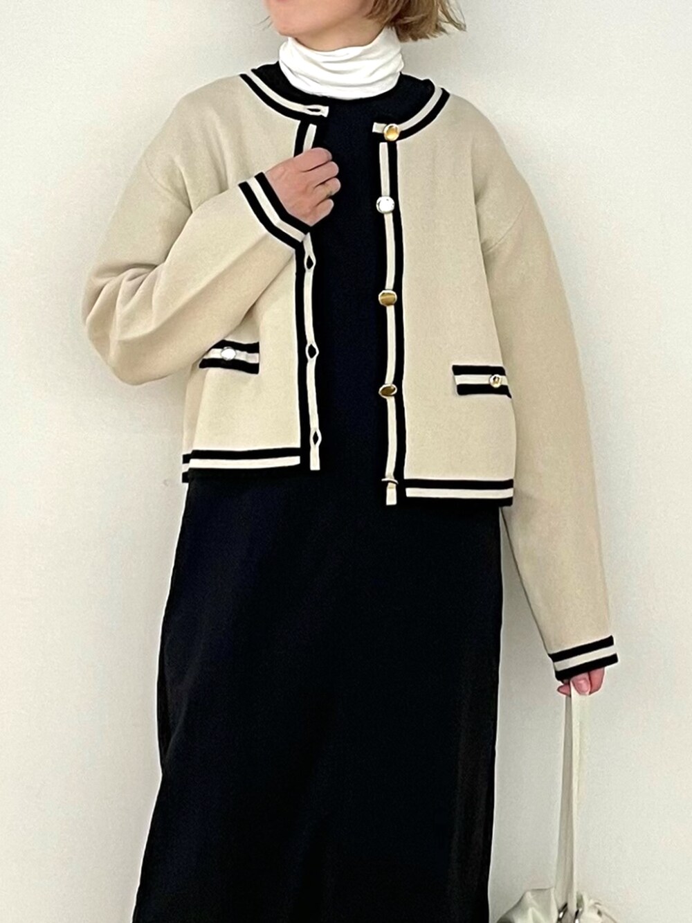 ブラック系のワンピース、ホワイト系のTシャツ/カットソー、ベージュ系のカーディガン/ボレロを着用したレディースの秋コーディネートの5枚目の写真