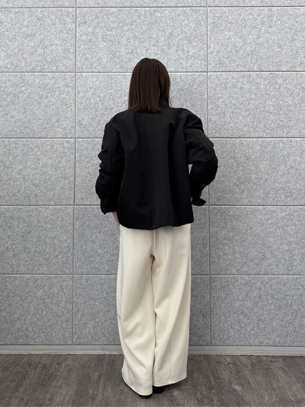 グレー系のニット/セーター、ブラック系のブルゾン、ホワイト系のその他パンツを着用したレディースの秋コーディネートの4枚目の写真