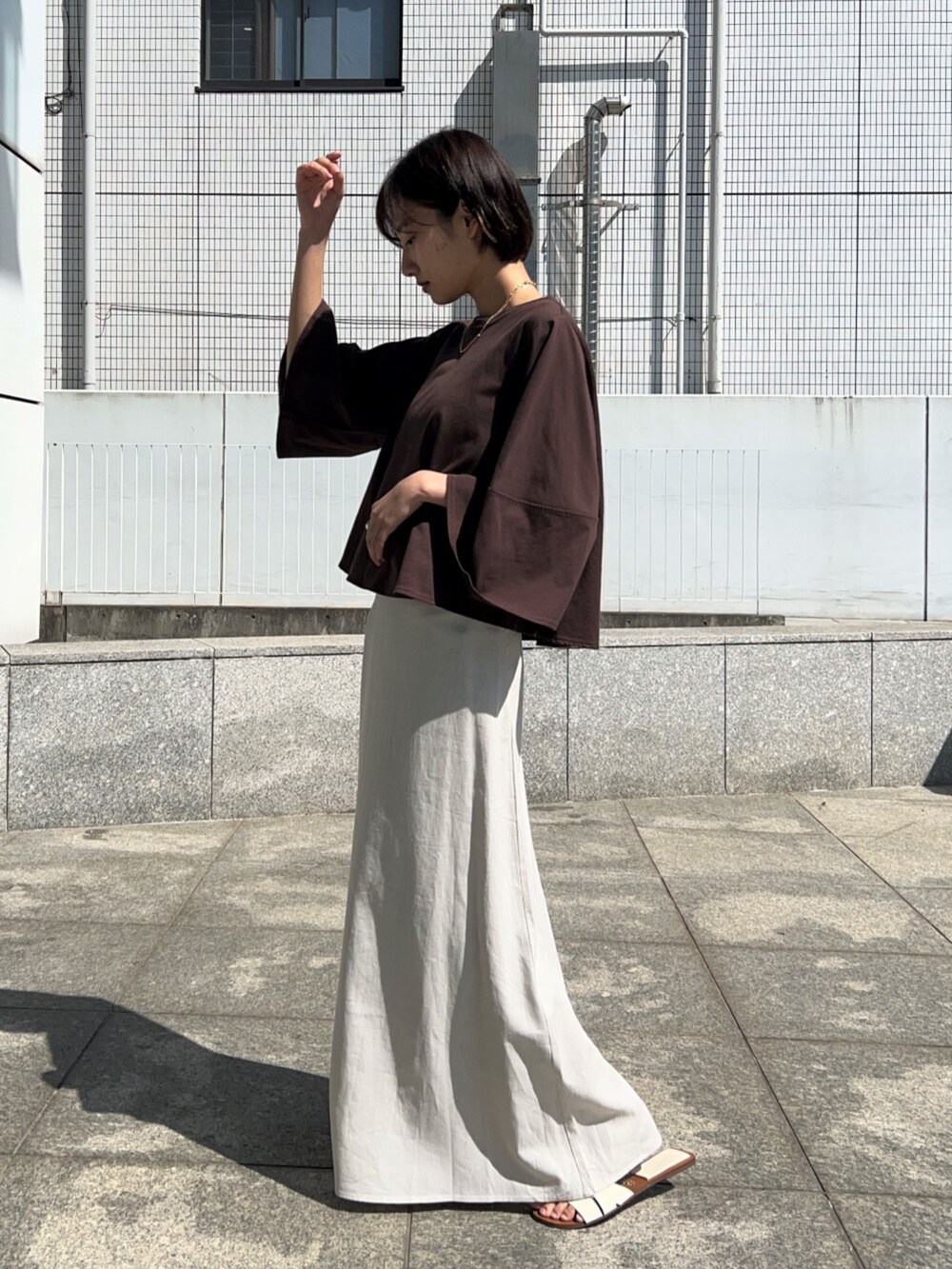 ホワイト系のスカート、ブラウン系のTシャツ/カットソーを着用したレディースの春コーディネートの3枚目の写真