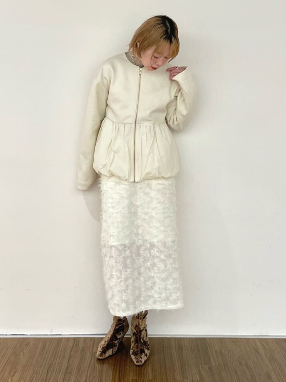 ホワイト系のスカート、ゴールド系のニット/セーター、ホワイト系のブルゾンを着用したレディースの冬コーディネートの2枚目の写真