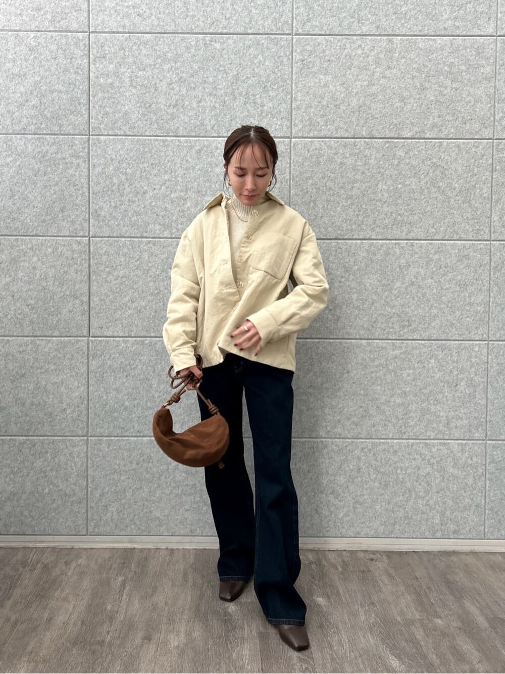 ベージュ系のブルゾン、ホワイト系のニット/セーター、ブルー系のデニムパンツを着用したレディースの冬コーディネートの2枚目の写真