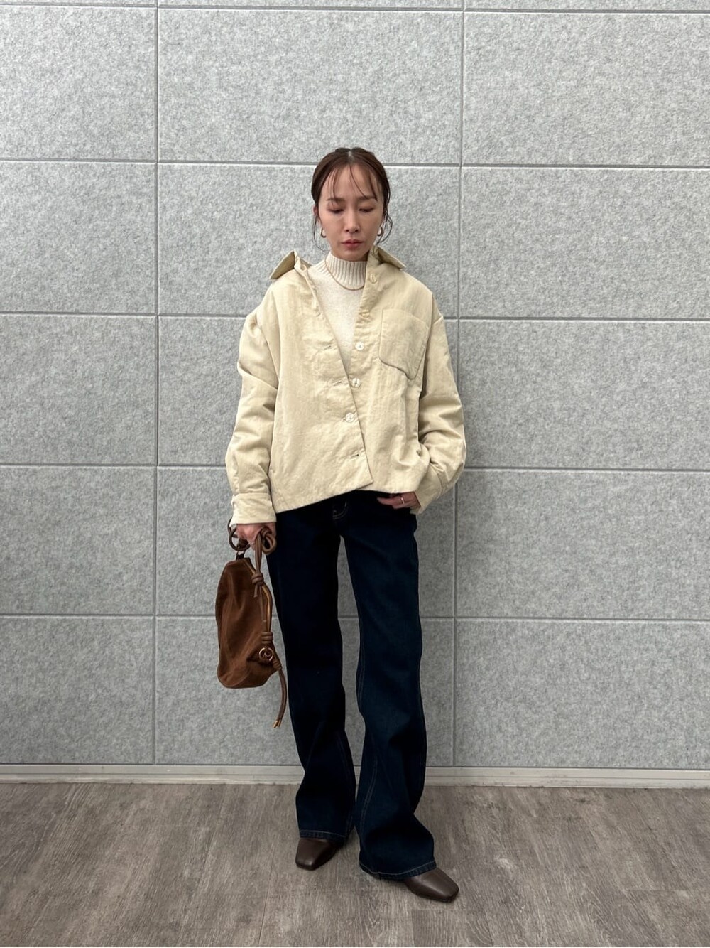 ベージュ系のブルゾン、ホワイト系のニット/セーター、ブルー系のデニムパンツを着用したレディースの冬コーディネートの3枚目の写真