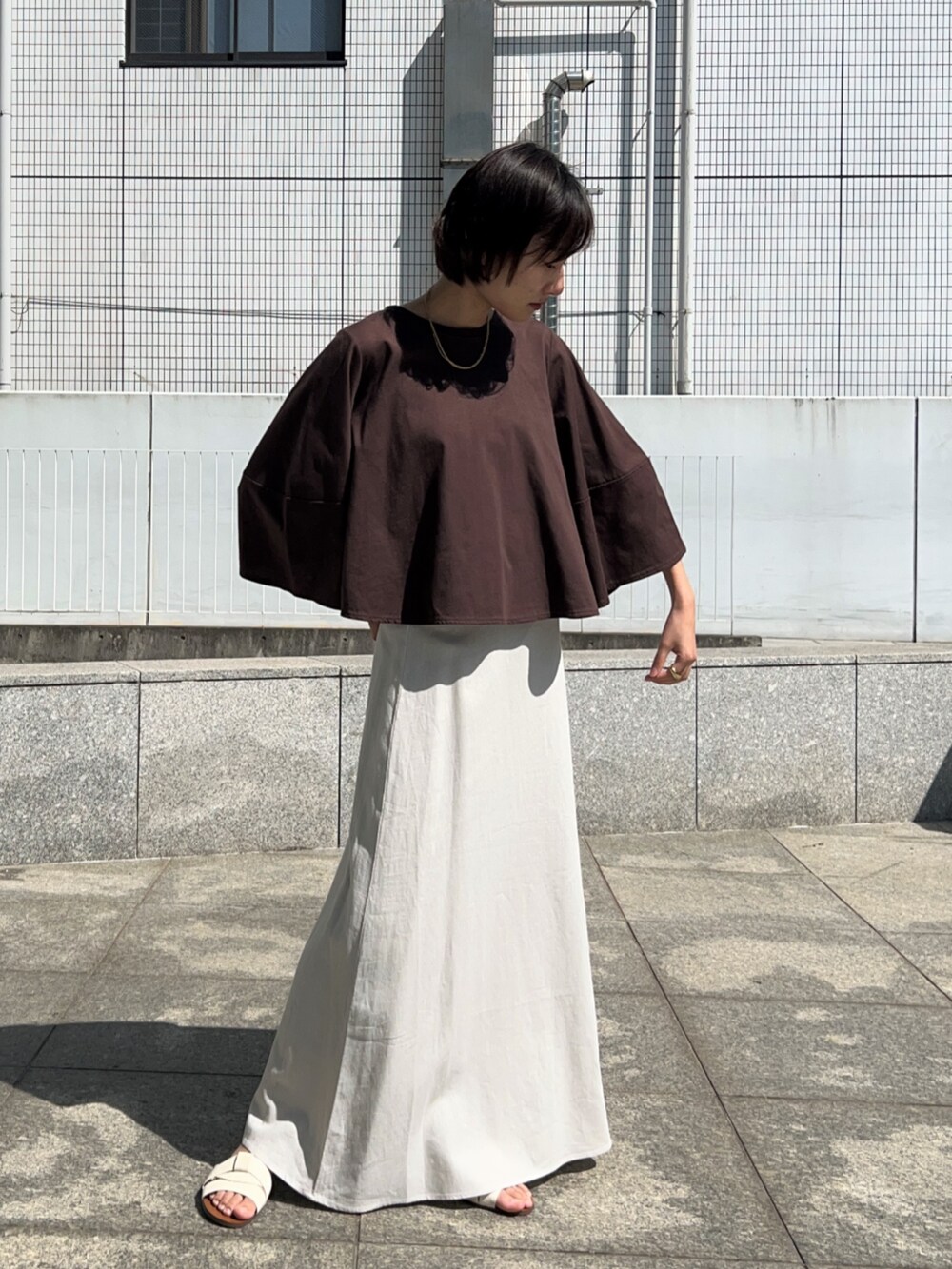 ホワイト系のスカート、ブラウン系のTシャツ/カットソーを着用したレディースの春コーディネートの5枚目の写真
