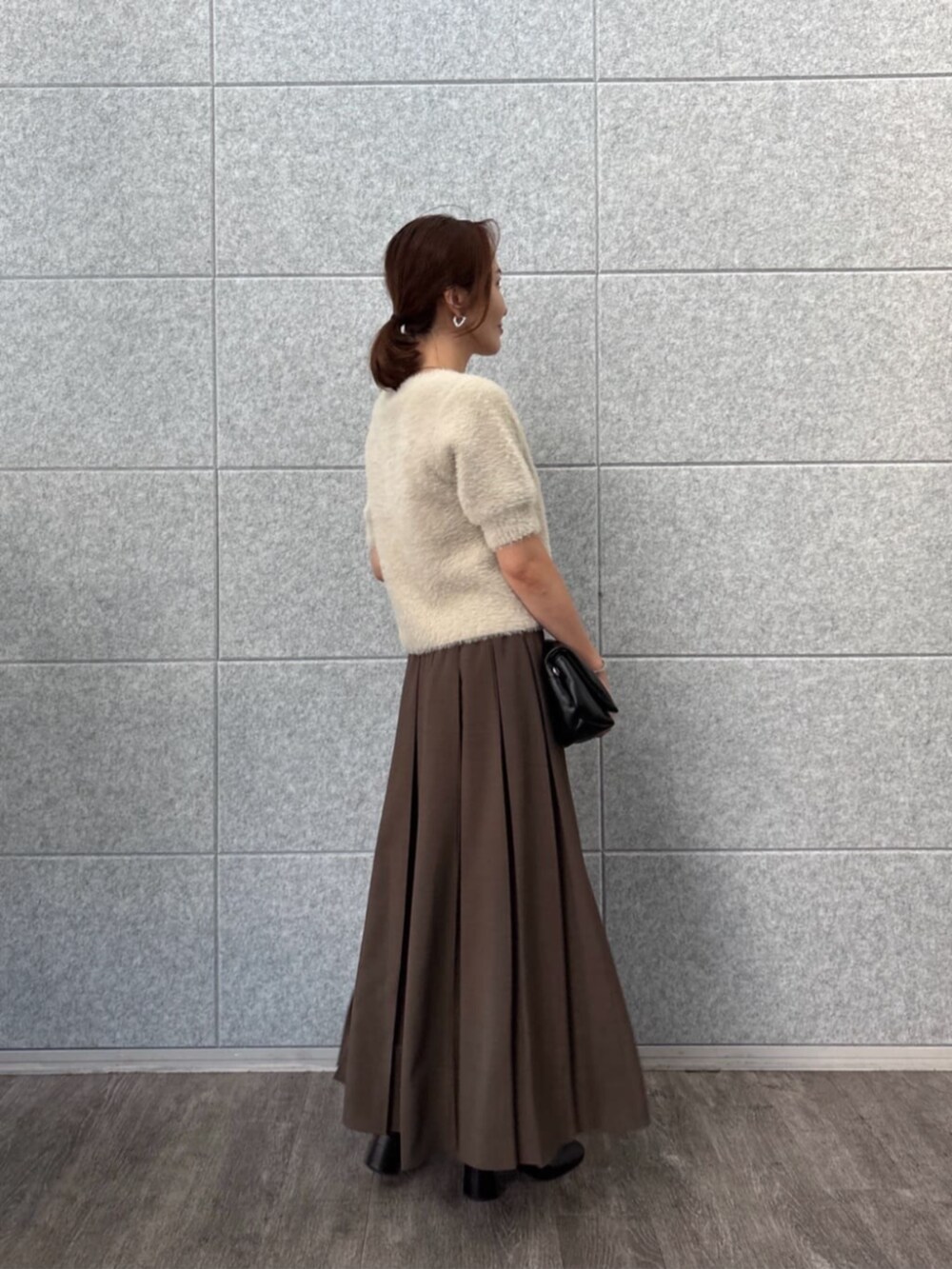 ベージュ系のニット/セーター、ブラウン系のスカートを着用したレディースの秋コーディネートの2枚目の写真