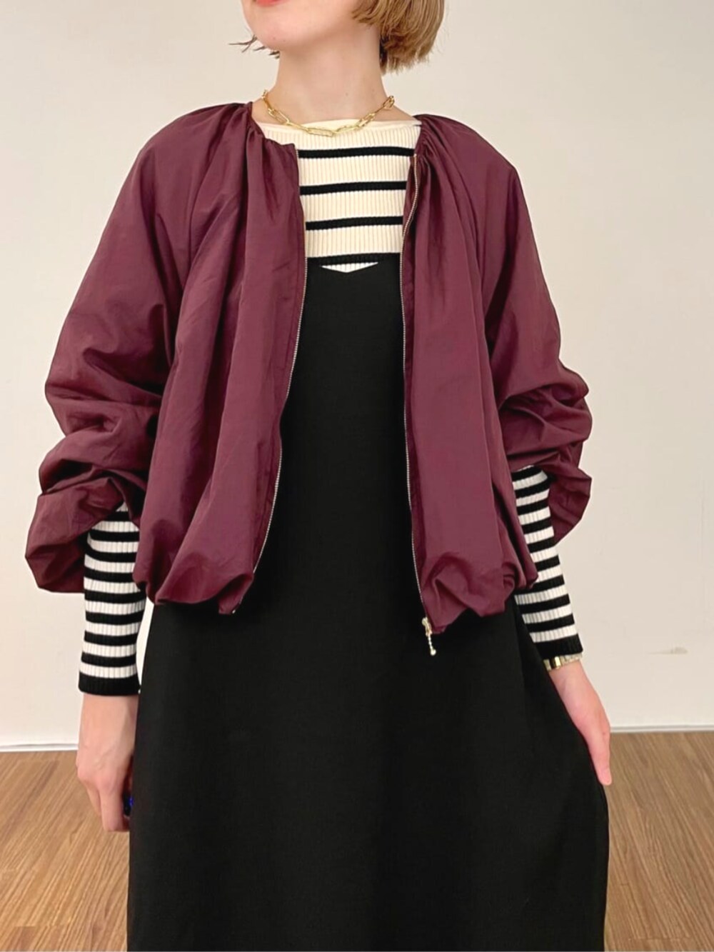 レッド系のブルゾン、ブラック系のワンピース、ベージュ系のニット/セーターを着用したレディースの秋コーディネートの7枚目の写真