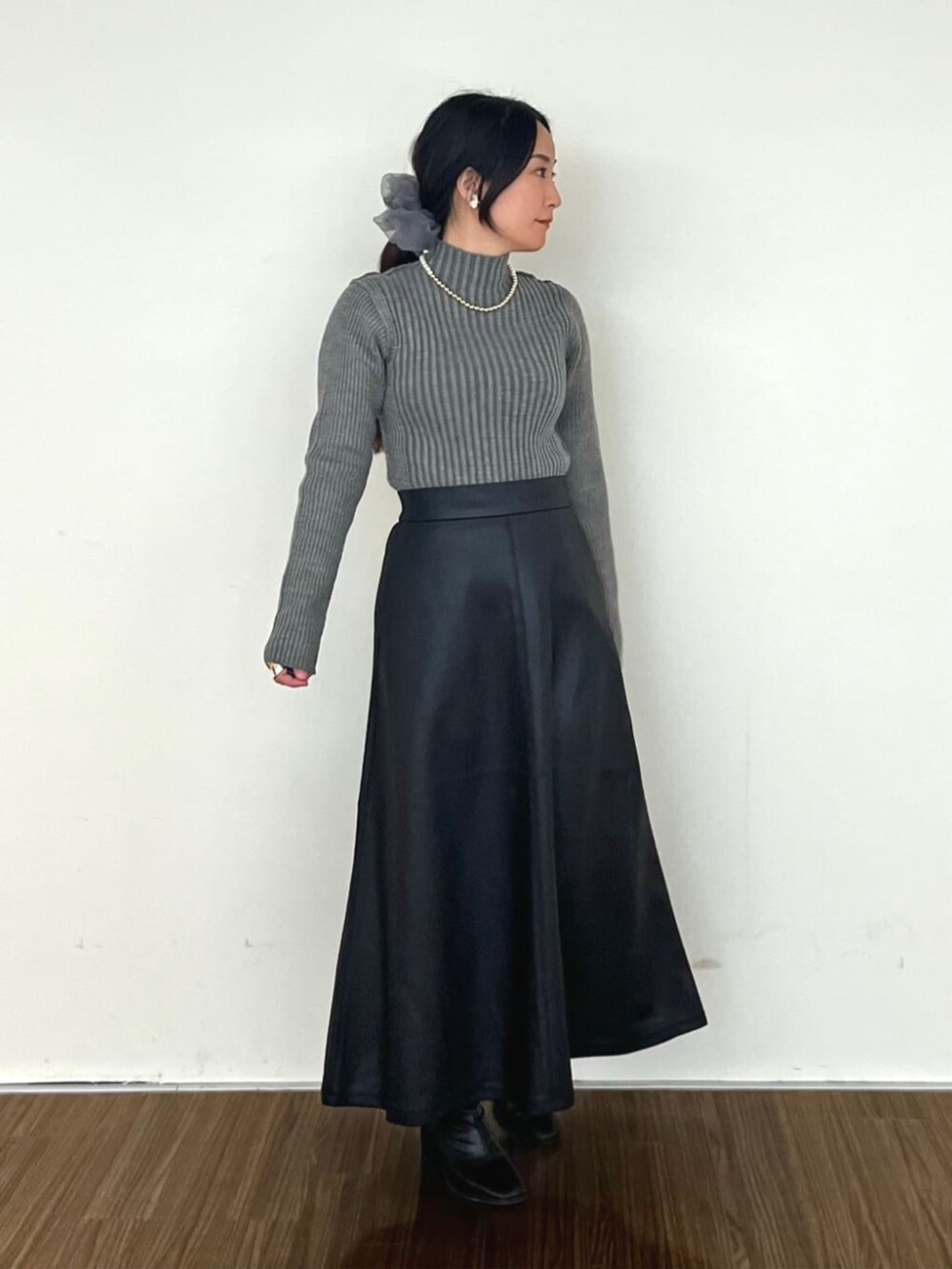 ブラック系のスカート、グレー系のニット/セーターを着用したレディースの冬コーディネートの2枚目の写真