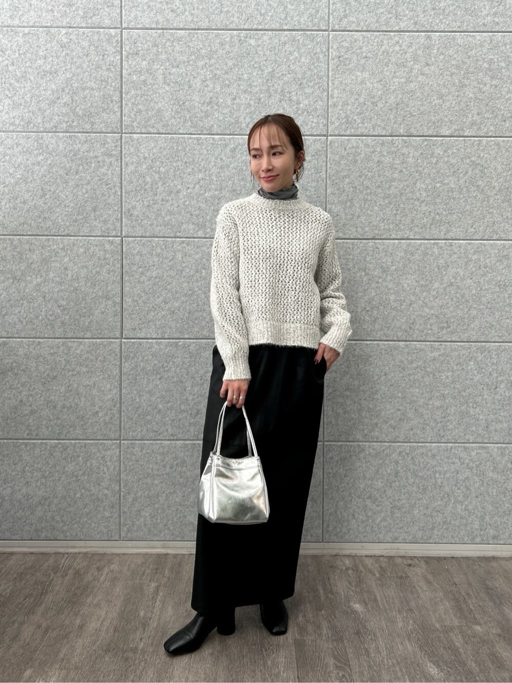 グレー系のニット/セーター、グレー系のTシャツ/カットソー、ブラック系のスカートを着用したレディースの冬コーディネートの3枚目の写真