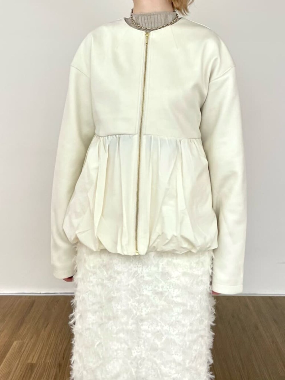 ホワイト系のスカート、ゴールド系のニット/セーター、ホワイト系のブルゾンを着用したレディースの冬コーディネートの4枚目の写真