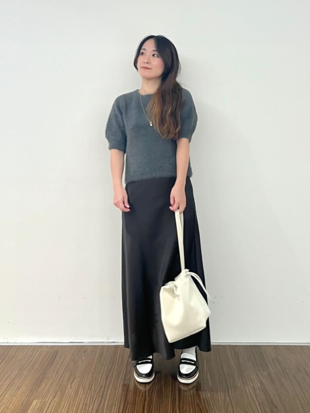 グレー系のニット/セーター、グレー系のスカートを着用したレディースの秋コーディネートの3枚目の写真