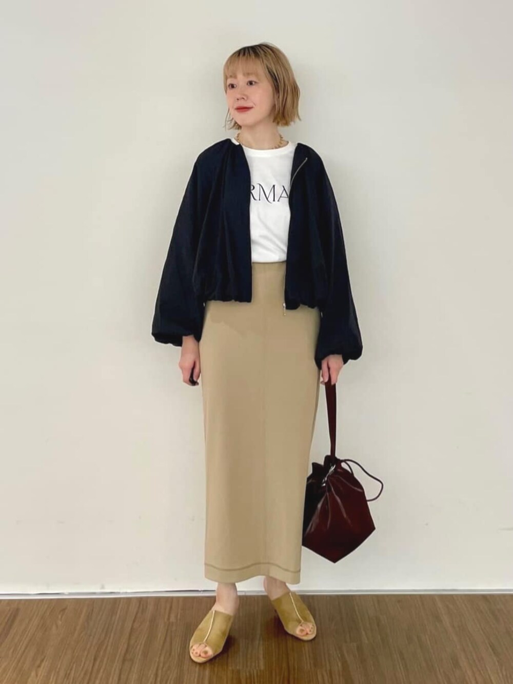 ブラック系のブルゾン、ブラウン系のスカート、ホワイト系のTシャツ/カットソーを着用したレディースの秋コーディネートの3枚目の写真