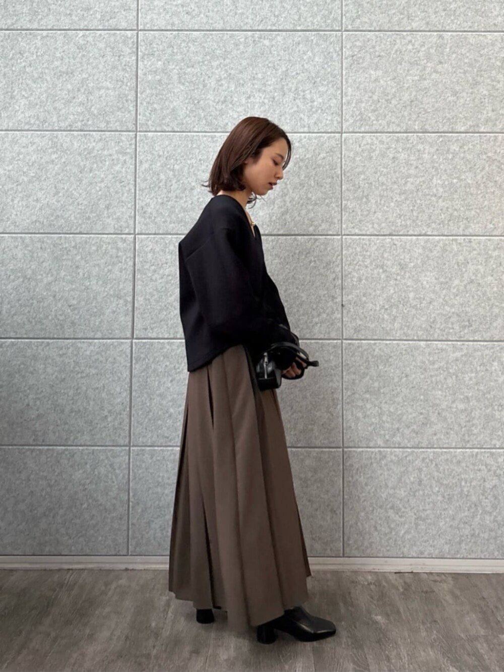 ブラウン系のスカート、ブラック系のTシャツ/カットソーを着用したレディースの秋コーディネートの3枚目の写真