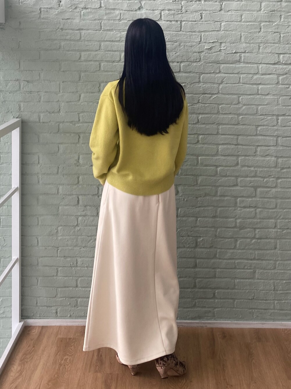ホワイト系のTシャツ/カットソー、ホワイト系のスカート、イエロー系のニット/セーターを着用したレディースの秋コーディネートの4枚目の写真
