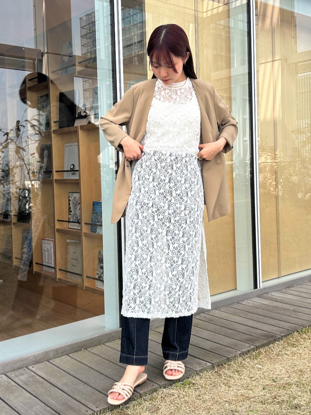 ブルー系のデニムパンツ、ベージュ系のノーカラージャケット、ホワイト系のタンクトップを着用したレディースの春コーディネートの2枚目の写真