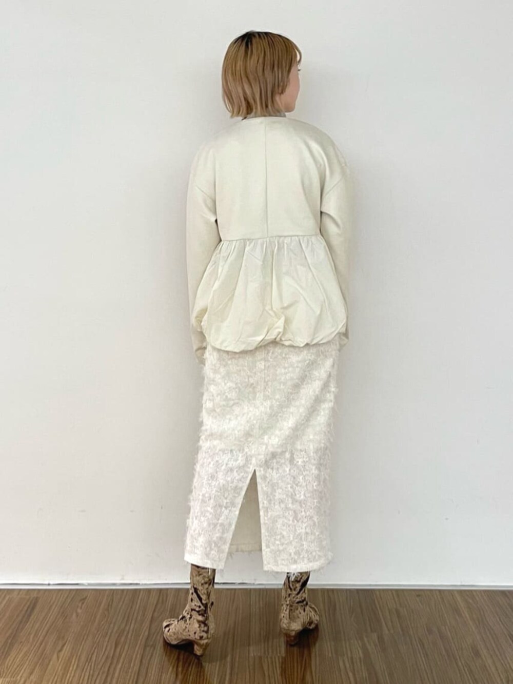 ホワイト系のスカート、ゴールド系のニット/セーター、ホワイト系のブルゾンを着用したレディースの冬コーディネートの3枚目の写真