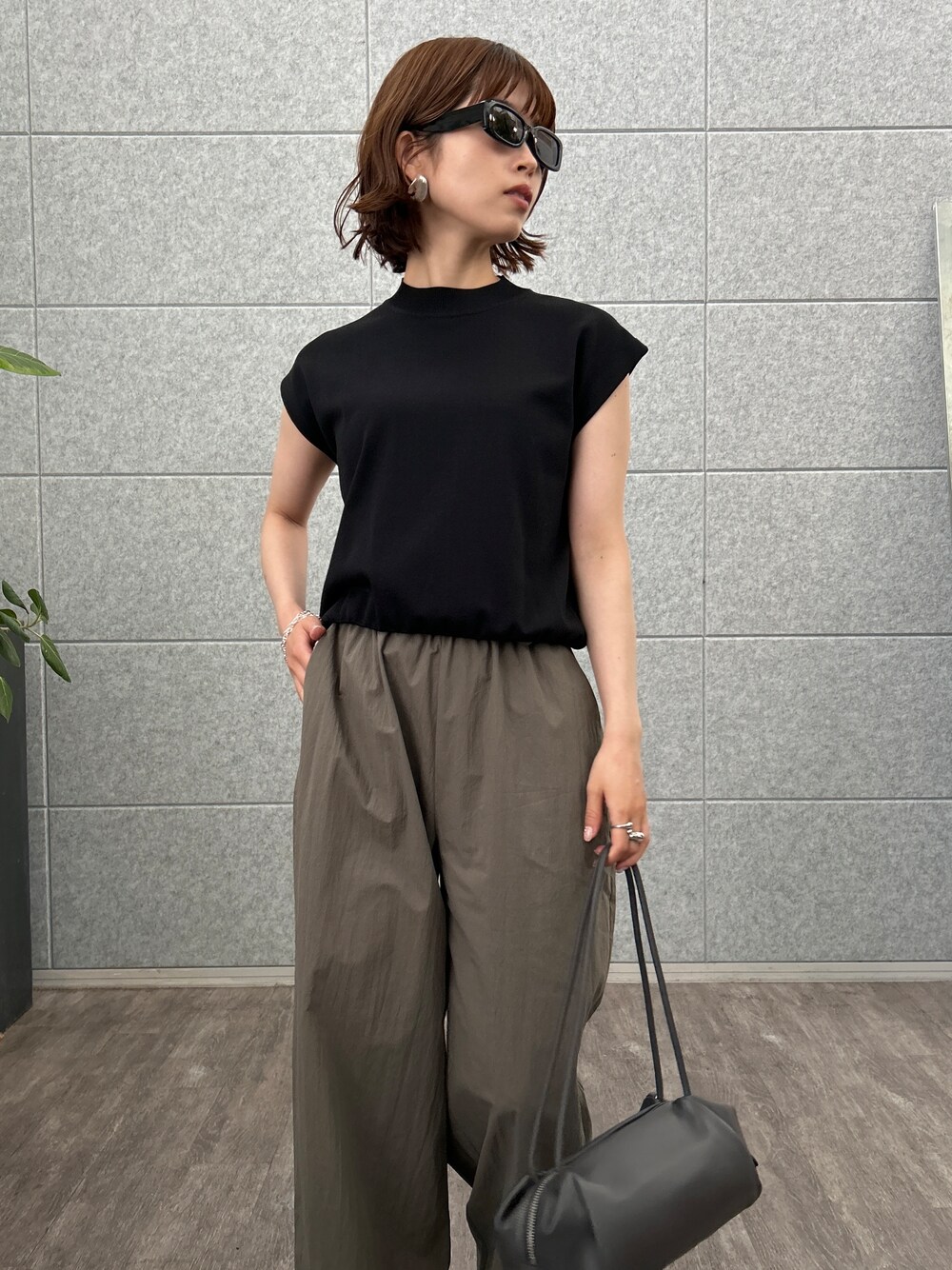 ブラック系のニット/セーター、グリーン系のその他パンツを着用したレディースの夏コーディネートの6枚目の写真